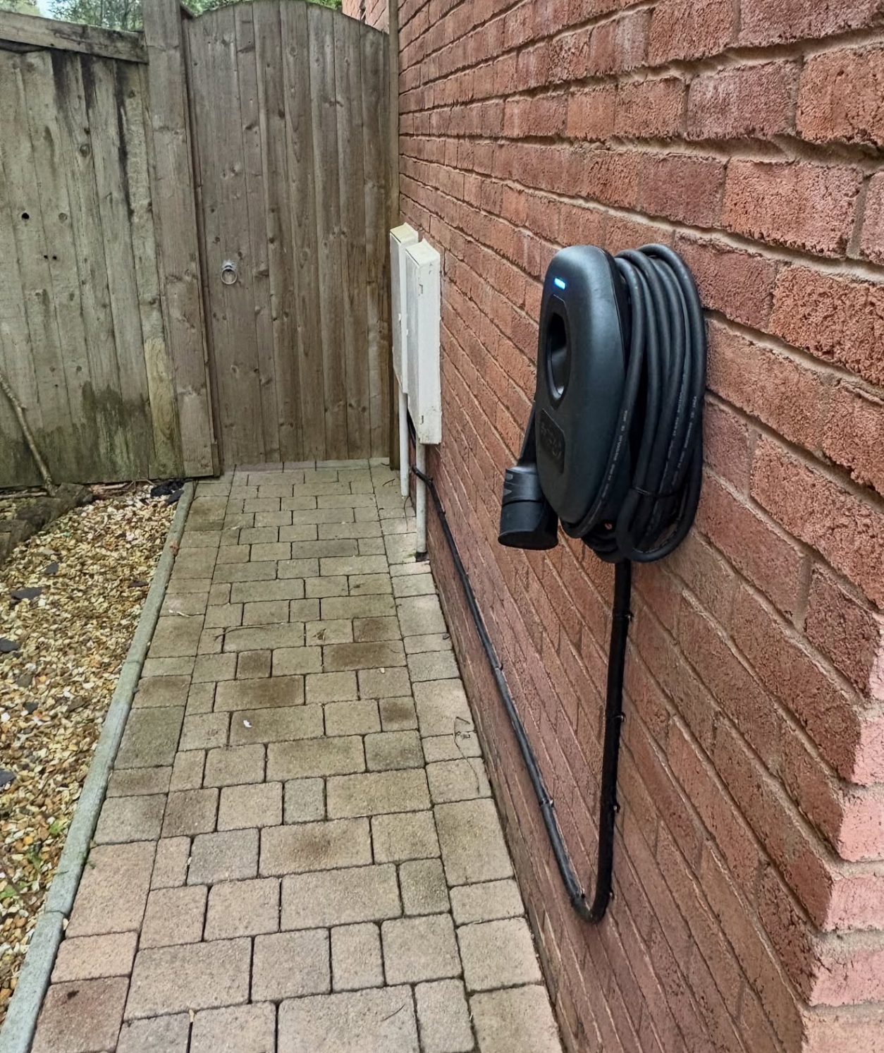 EV charger and cable route in a narrow side passage of a brick house